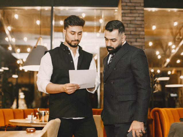 Handsome man in a black suit. Businessmen working in a cafe. People stands and looks in a documents.